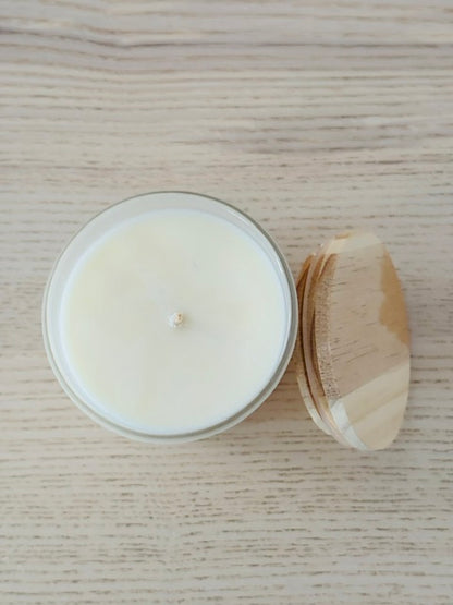 Candle in a glass jar with a wooden lid on a wooden surface